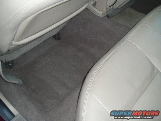 Car interior with tan leather seats and gray carpeted floor. Watermark 'SUPERMOTORS www.supermotors.net' visible