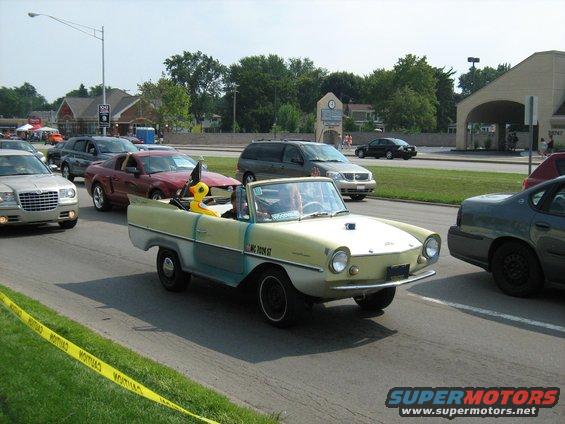 Yellow and white amphibious car with a duck figure in the passenger seat