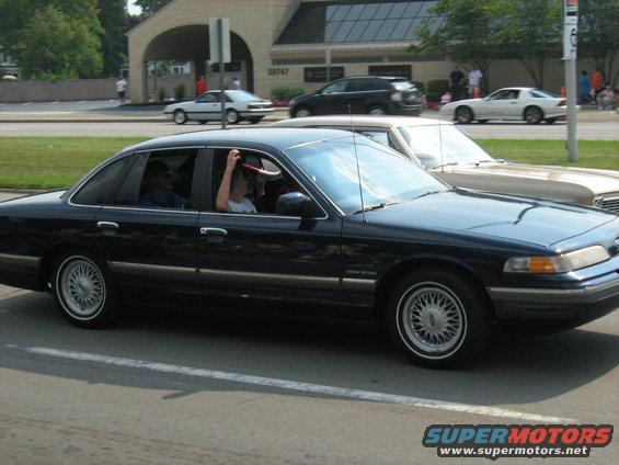 Dark sedan with chrome trim and wire wheels, seen from the side