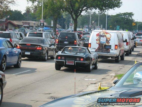 Black Corvette Stingray in traffic, van with graphic behind it
