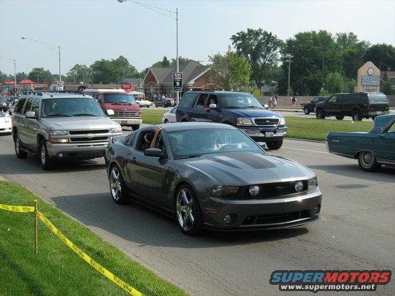 Gray Ford Mustang driving in traffic, other SUVs and vans around