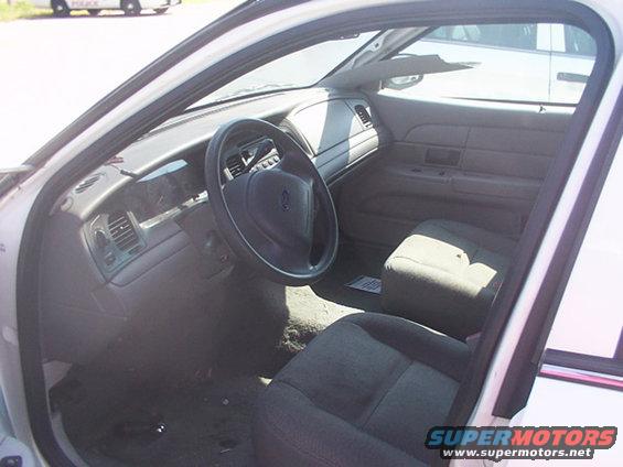 Interior of a white 2003 Ford Crown Victoria, showing the dashboard, steering wheel, and front seats