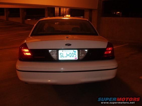 Rear of a white Ford Crown Victoria at night. License plate is visible