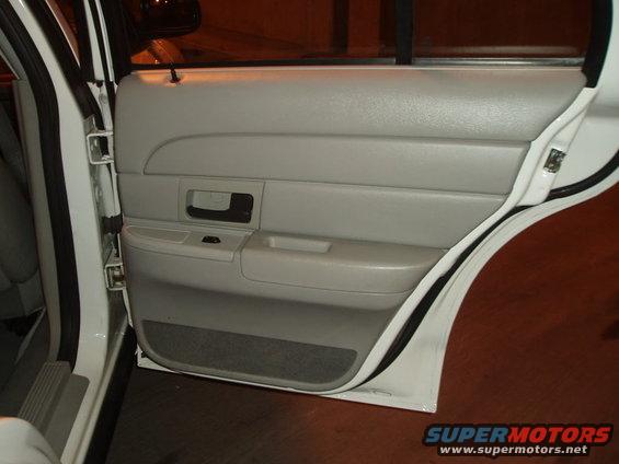 White car interior rear door panel with gray upholstery and black door handle
