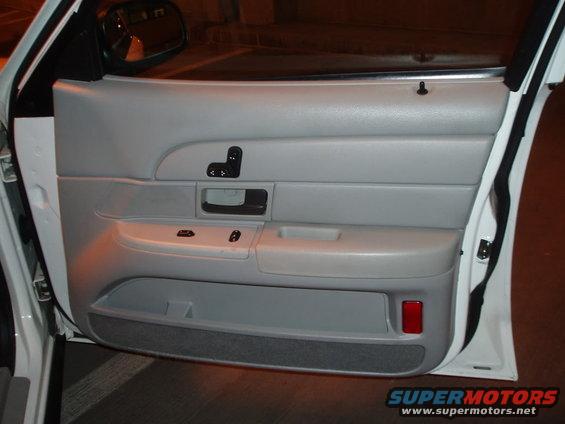Gray car door panel with window controls and a red reflector