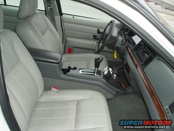 Light gray leather interior of a 2003 Ford Crown Victoria, showing front seats, dashboard, and center console