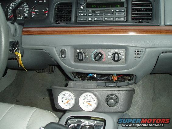 2003 Ford Crown Victoria interior showing dashboard, steering wheel, and aftermarket oil and voltage gauges