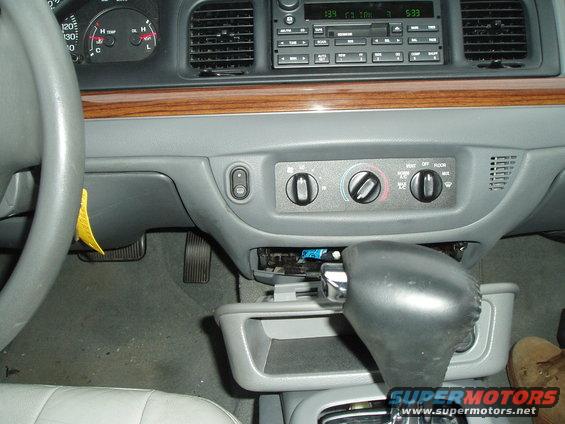 Dashboard and center console of a 2003 Ford Crown Victoria, showing the steering wheel, radio, climate controls, and gear shifter