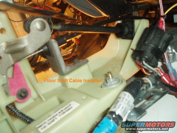 Close-up of car interior shift mechanism with "Floor Shift Cable Installed" text overlay