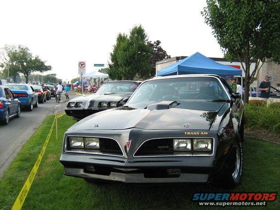 Black Pontiac Trans Am with scoop on hood, parked next to other cars