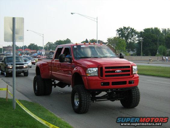 Red lifted Ford F-350 Super Duty truck, 3q front view. Number 5 visible on windshield