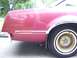 1979 Ford Thunderbird - The rear quarter panel and wheel of a maroon vehicle are visible, chrome trim and gold turbine-style wheels.