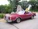 1979 Ford Thunderbird - A maroon 1977 Ford Thunderbird is parked on a paved surface with trees and a stone monument behind it.