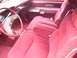 1979 Ford Thunderbird - The plush red interior of a vintage automobile features velour seating and wood-grain accents on the steering wheel.