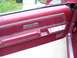 1979 Ford Thunderbird - The interior door panel of a maroon vehicle shows velour upholstery and wood trim details.