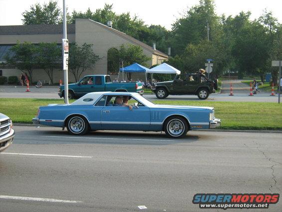 Blue 1977 Mercury Cougar coupe with white vinyl roof driving on a street