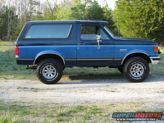 Blue and black Ford Bronco parked on a dirt road