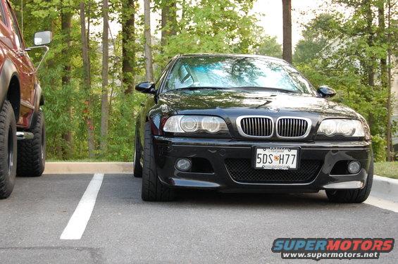 Front view of a black BMW M3 parked next to a brown SUV. License plate reads 5DS H77