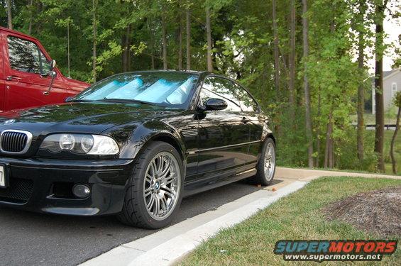 Black 2002 BMW M3 coupe parked next to a red truck, front 3/4 view