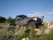 1984 Ford Bronco II - A heavily modified Ford Bronco II navigates a rocky, off-road path under a clear blue sky.