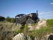 1984 Ford Bronco II - A heavily modified off-road vehicle navigates a rocky terrain under a clear blue sky.