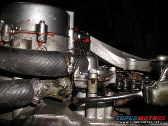 Motorcycle engine with hoses, chain, and oil residue