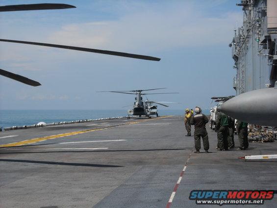 Helicopters on an aircraft carrier deck with crew members nearby