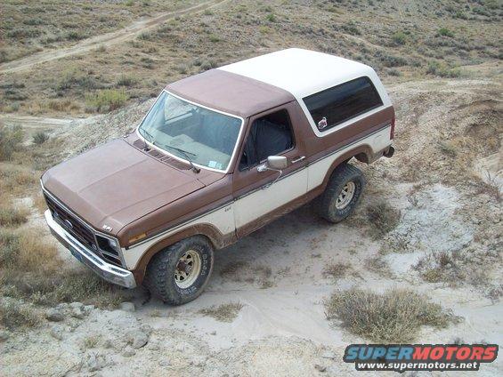 Brown and white Ford Bronco on dirt road
