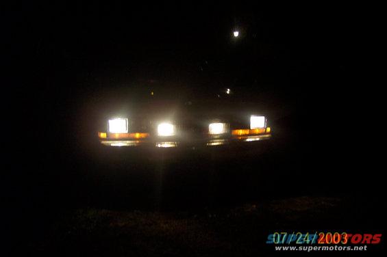 Car headlights and amber turn signals illuminated at night