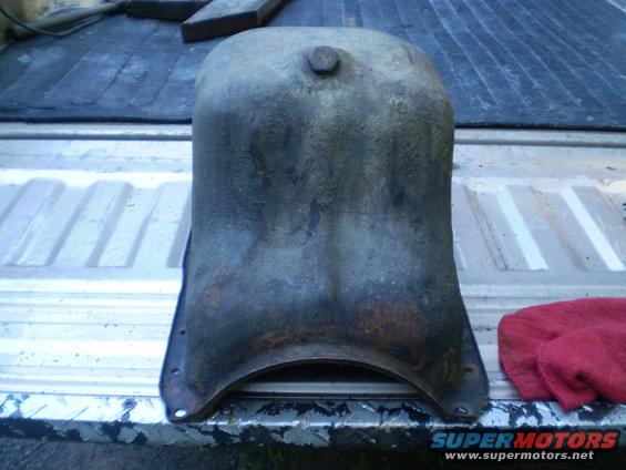 Rusty oil pan with a bolt on top, resting on a truck bed
