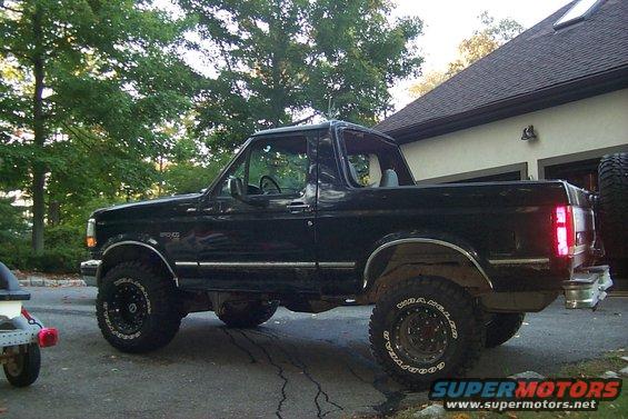 Black 1992 Ford Bronco parked on a driveway, side view, lifted suspension, off-road tires