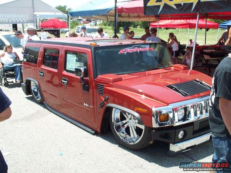 Red Hummer H2 with chrome wheels, lowered suspension, and custom hood scoop