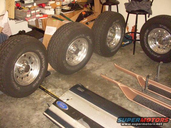 Four tires on chrome rims, two running boards, and a Ford emblem on a silver and black panel