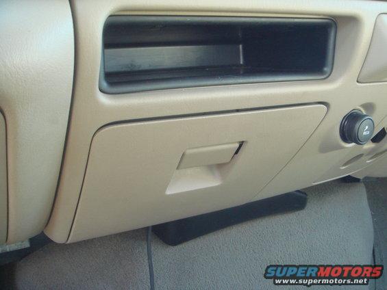 Tan dashboard with open storage compartment and closed glove box. Ashtray with cigarette lighter is visible