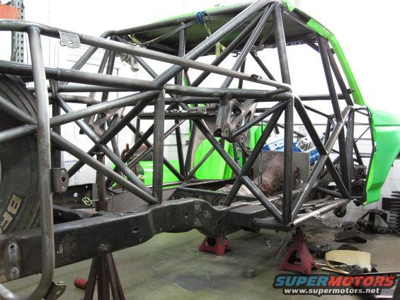 Vehicle frame with extensive custom roll cage fabrication, green body panels visible
