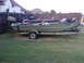 1993 Ford C-150 (Centurion Conversions) - Two boats are parked on trailers in a grassy yard next to a wooden fence.