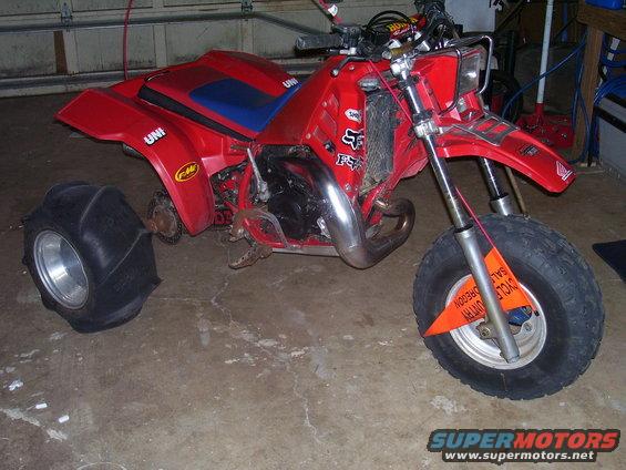 Red three-wheeled ATV with sand tire on back and knobby tire on front. Orange sale tag on front wheel