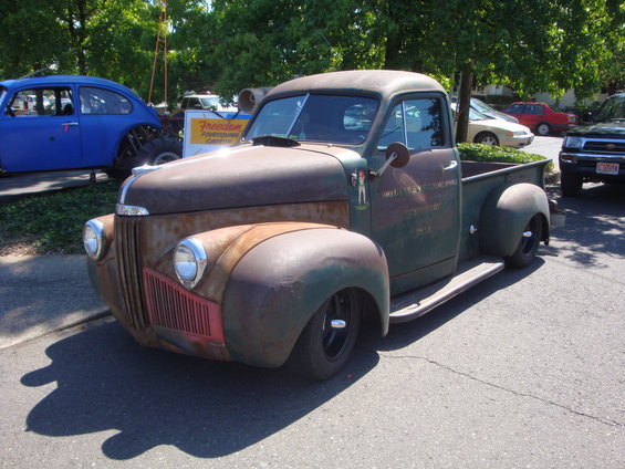 Rat rod pickup truck with faded green paint and red grille detail