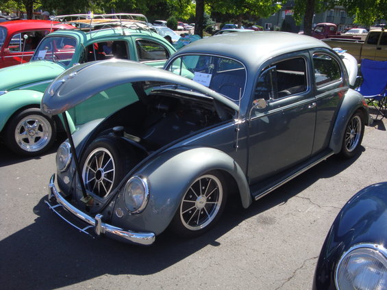 Gray Volkswagen Beetle with hood open, showing spare tire. Chrome bumper and custom wheels visible