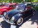 1964 Ford Fairlane - A black Volkswagen Beetle is displayed at a show next to a red Beetle.