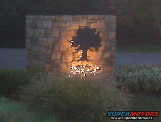 stone monument with tree cutout and lights at base