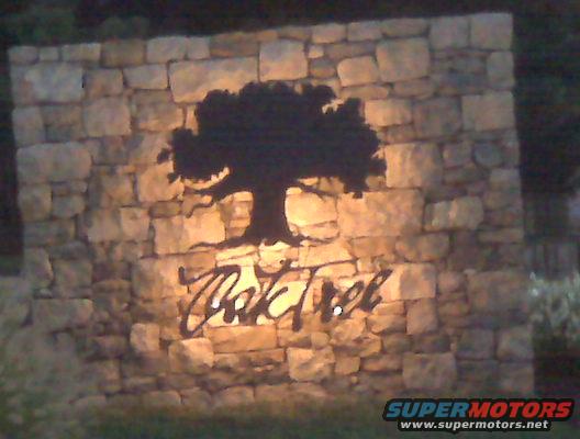 Stone wall sign with a silhouette of a tree and the words "Oak Tree" illuminated