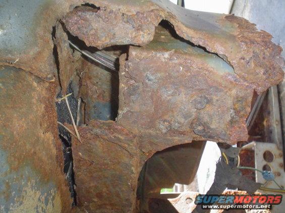 Heavily rusted metal frame and body panel with visible wires and debris. Supermotors.net watermark
