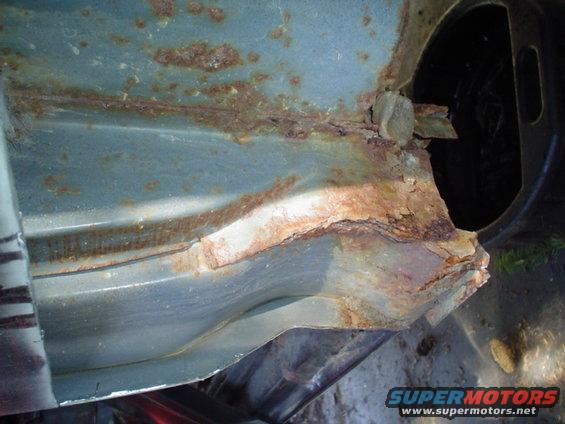 Heavily rusted metal panel, likely from a vehicle's undercarriage