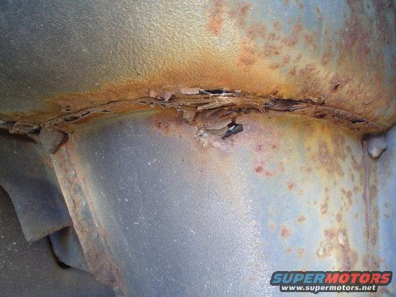close-up of heavily rusted metal on a vehicle frame, showing flaking and holes