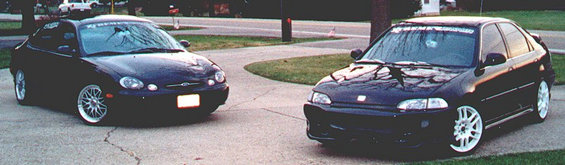 1999 Ford Taurus and a dark sedan parked on a driveway
