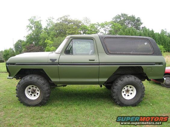 Green 1978 Ford Bronco with black top and large off-road tires, side view