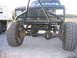 1984 Ford Bronco II - This heavily modified truck features a custom roll cage and beefy off-road tires, with a dump truck visible in the background.