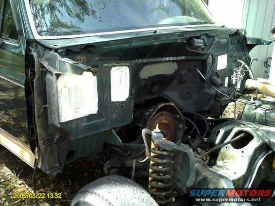 Green vehicle chassis with exposed engine bay, front suspension, and tire