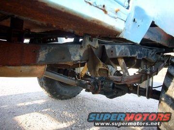 Undercarriage of a light blue vehicle showing rust and suspension components